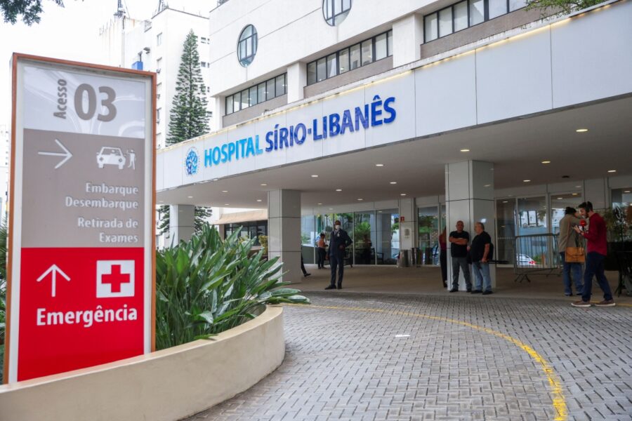 Entrada do Hospital Sírio-Libanês, incluindo sinalização para acesso e emergência, mostrando a estrutura e movimento no local.