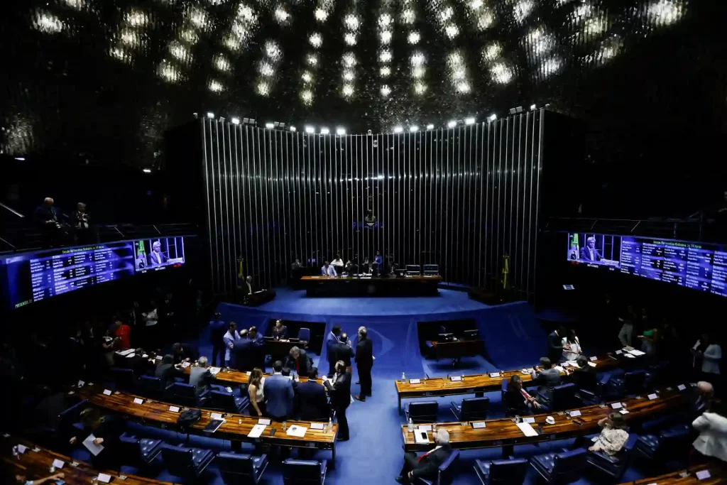 Antiga foto do plenário do Senado Federal do Brasil, onde se pode ver senadores em atividade e a estrutura arquitetônica moderna do espaço, demonstrando a importância da política brasileira.