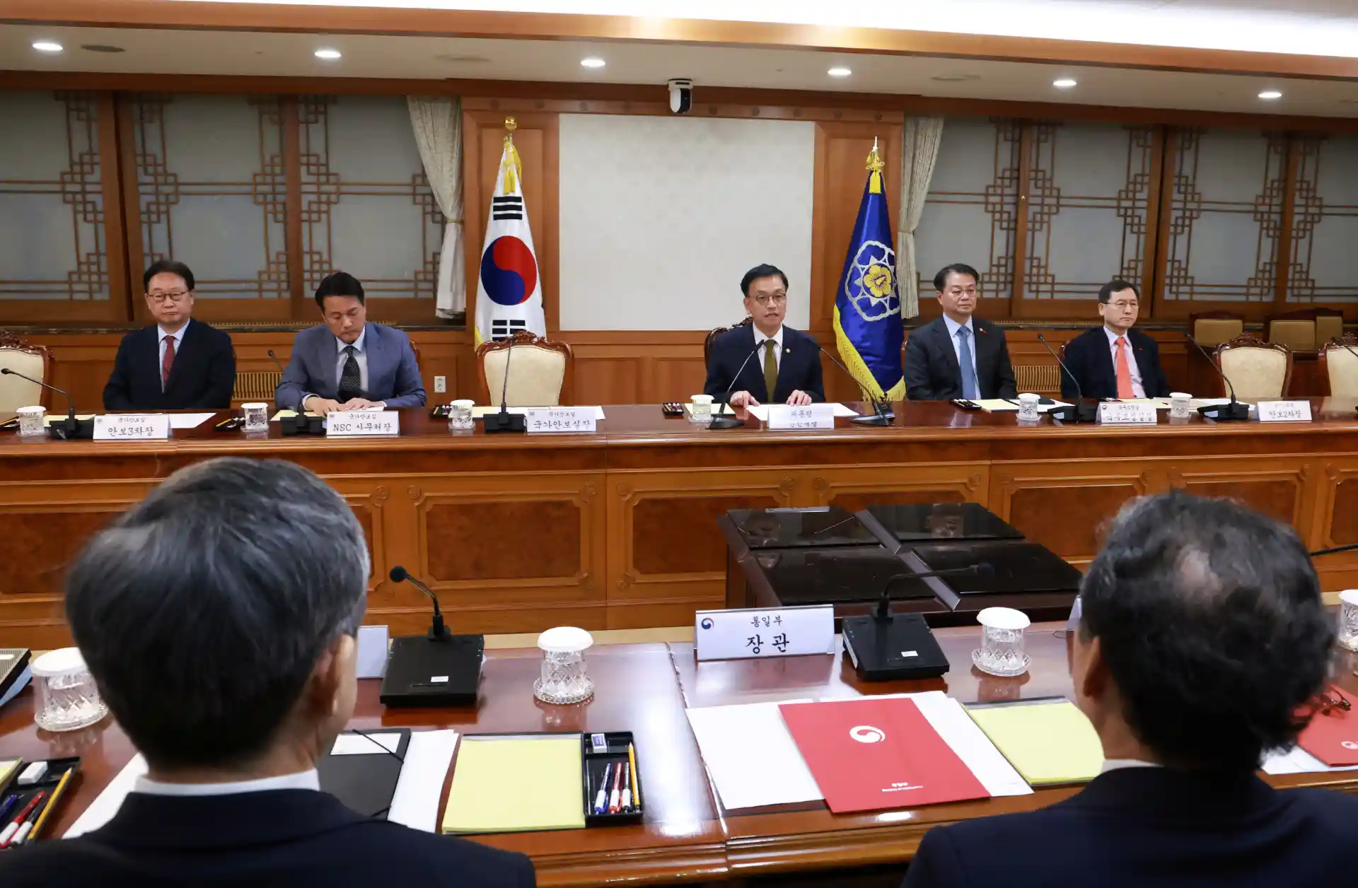 Reunião de líderes políticos na Coreia do Sul, com bandeiras do país visíveis ao fundo e mesa de conferência organizada.