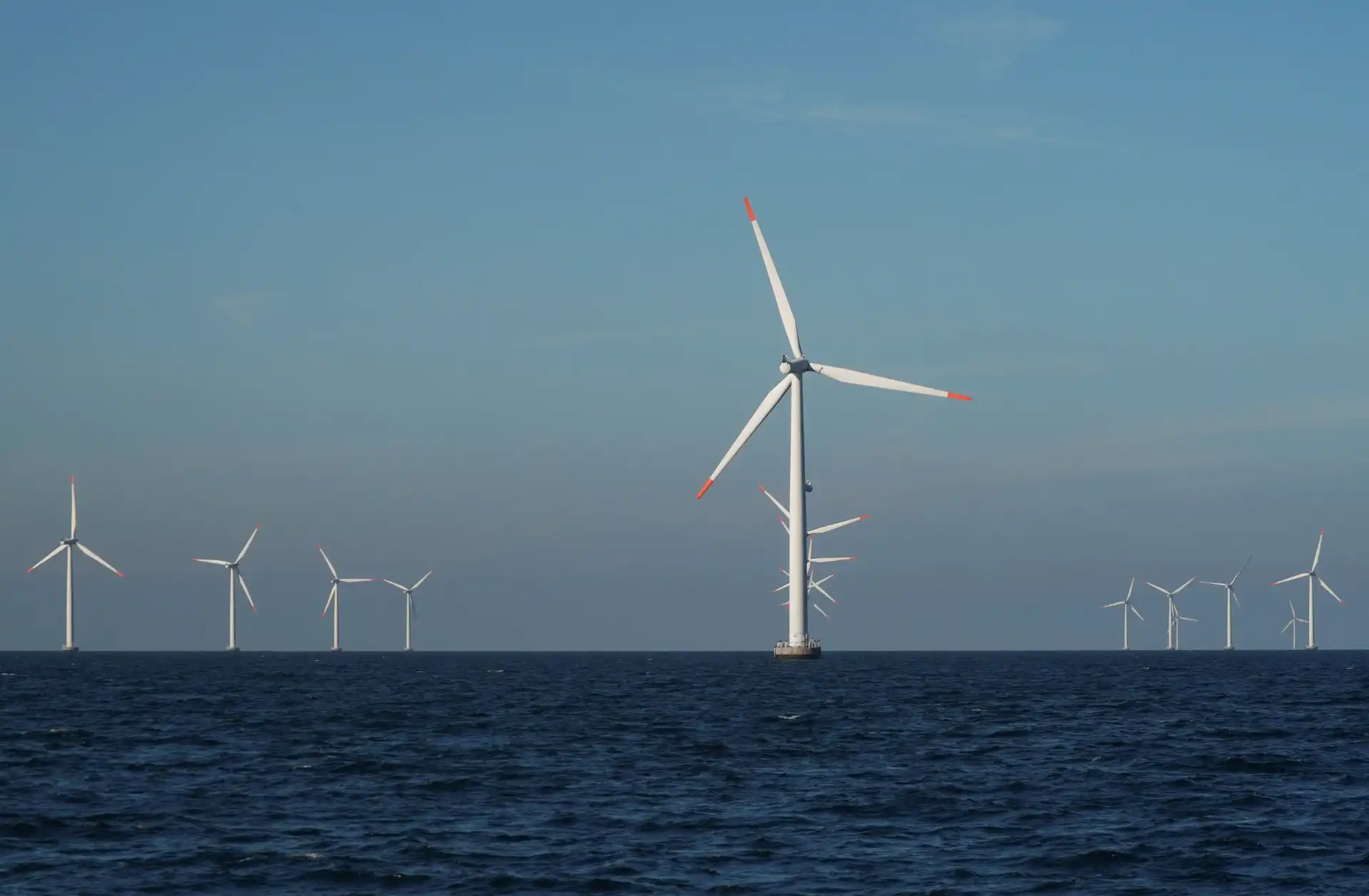 Imagem de turbinas eólicas em um ambiente marinho, evidenciando a energia renovável e a sustentabilidade. As turbinas geram eletricidade aproveitando a força do vento.