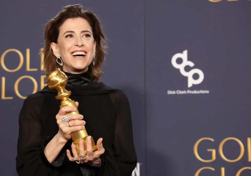 Atriz sorrindo com um Globo de Ouro na mão durante a premiação, celebrando seu reconhecimento na indústria do entretenimento.