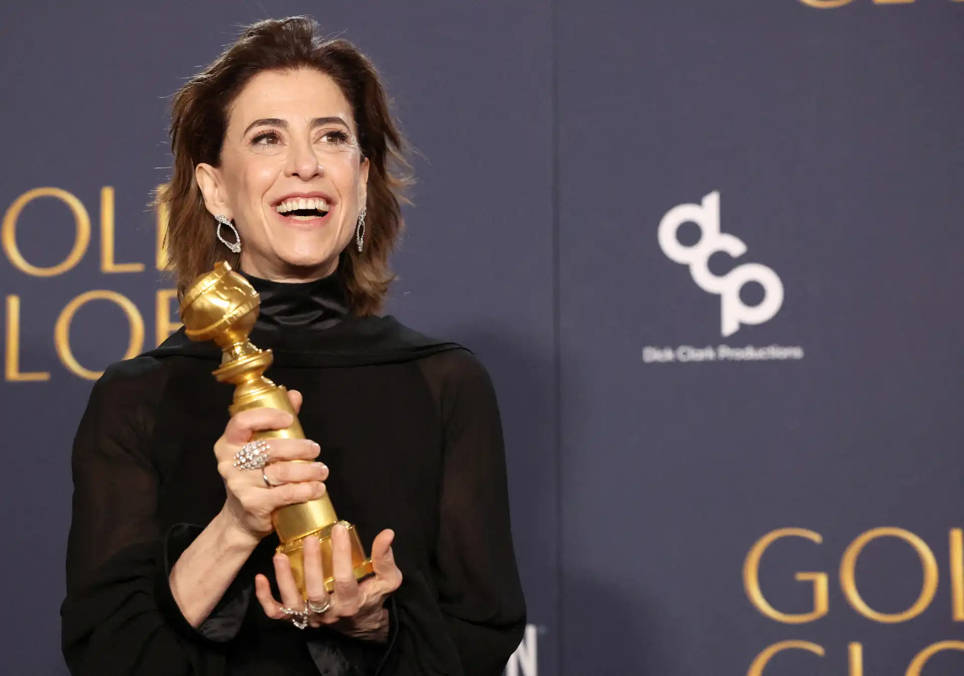 Atriz sorrindo com um Globo de Ouro na mão durante a premiação, celebrando seu reconhecimento na indústria do entretenimento.