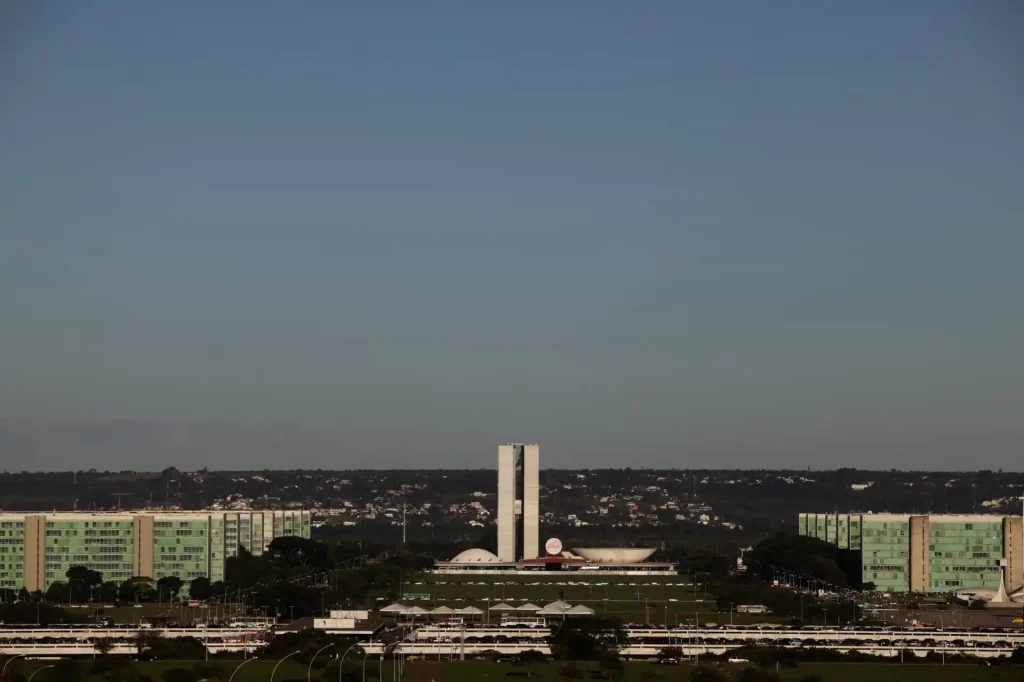 Vista do Congresso Nacional do Brasil, em Brasília, com o céu claro e a arquitetura moderna da cidade ao fundo.