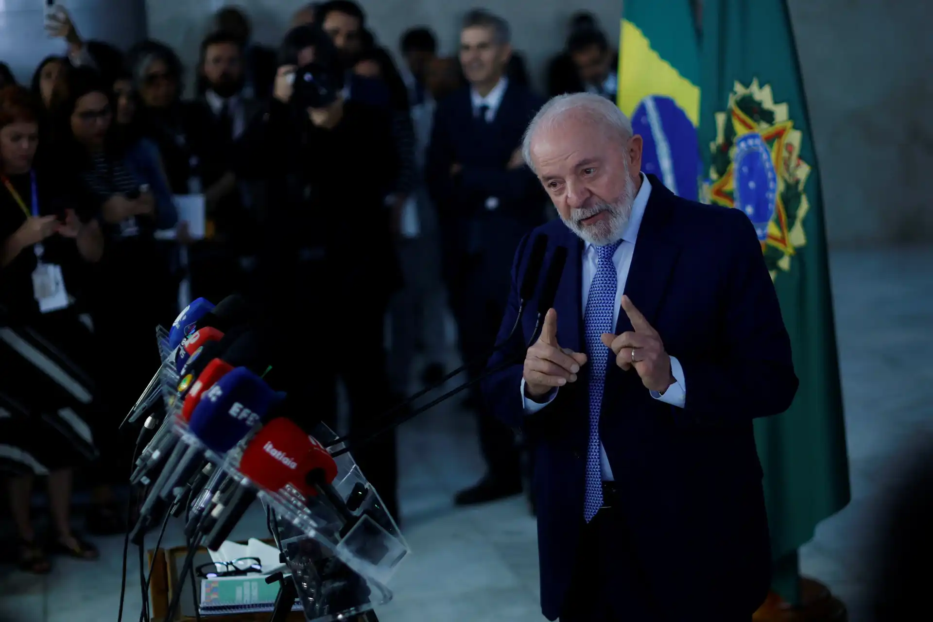 Discurso de Lula em coletiva de imprensa com a bandeira do Brasil ao fundo, destacando sua postura e ênfase em suas falas.