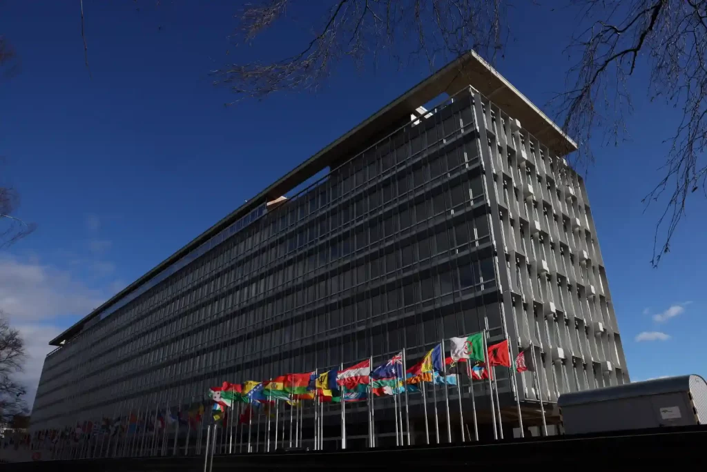 Vista do edifício moderno com bandeiras de diversos países em destaque, simbolizando a diversidade e a união internacional.