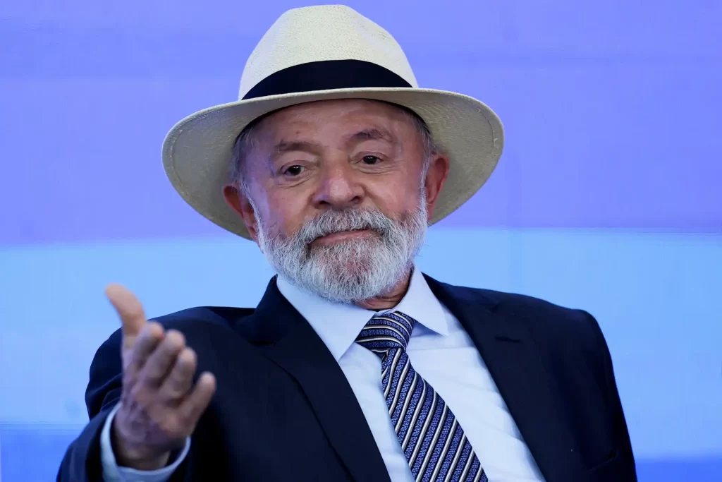 Imagem do presidente Lula usando um chapéu de palha, em um evento. Ele sorri e apresenta uma postura amigável, destacando sua presença carismática.