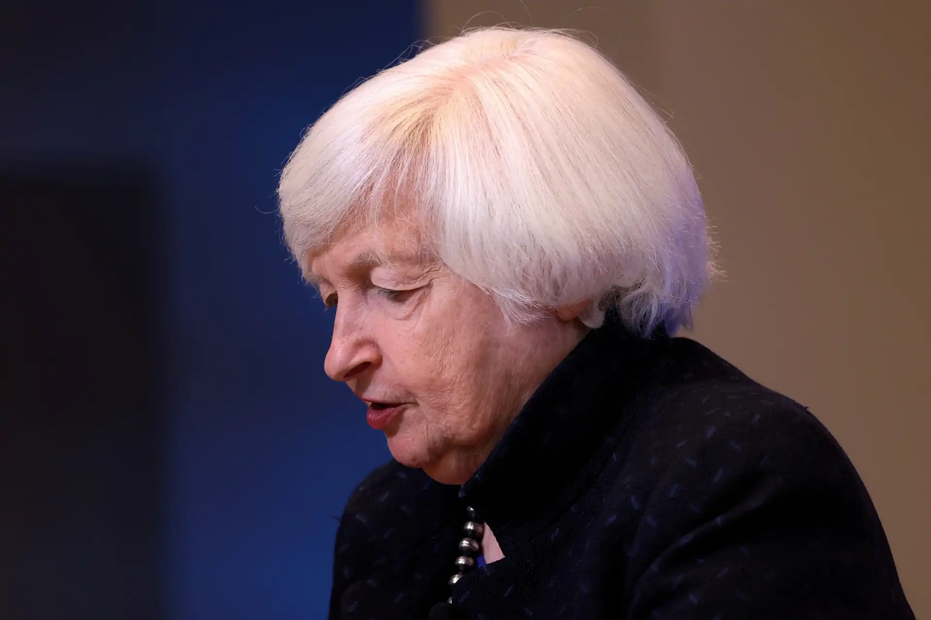 Imagem de Janet Yellen, destacando sua expressão reflexiva durante um evento, simbolizando a importância de suas contribuições econômicas e sua posição como Secretária do Tesouro dos EUA.