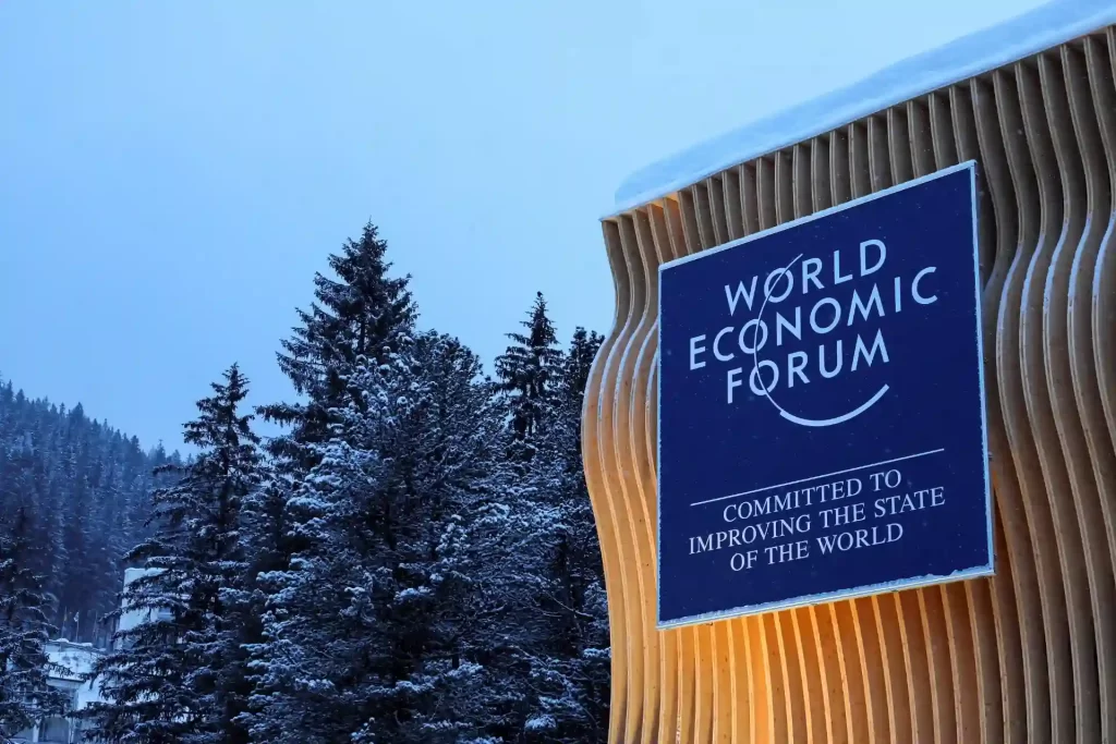 Placa do Fórum Econômico Mundial, destacando seu compromisso em melhorar o estado do mundo com a bela paisagem de inverno ao fundo.