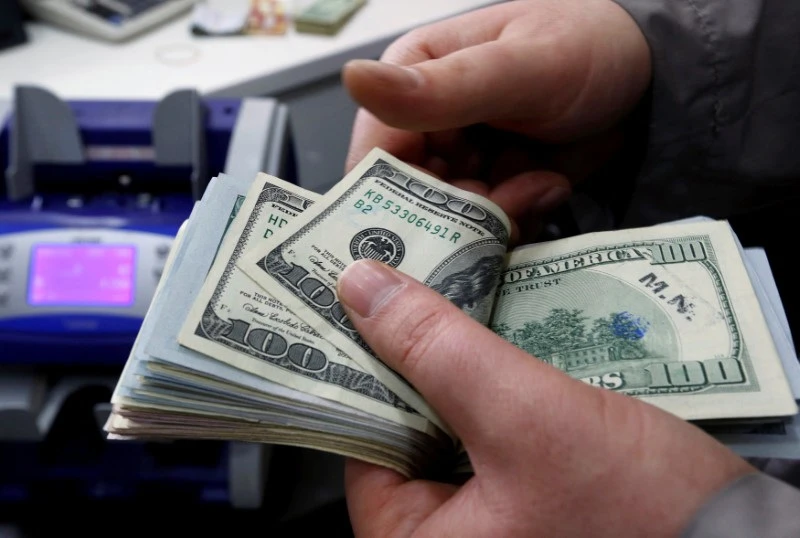 Pessoa contando notas de dólares, destacando a importância do dinheiro e suas transações. A cena mostra a interação financeira com um maquinário ao fundo.
