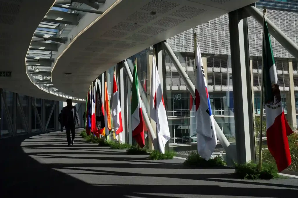 Corredor iluminado com bandeiras de vários países em exibição, simbolizando a diversidade cultural e a colaboração internacional.