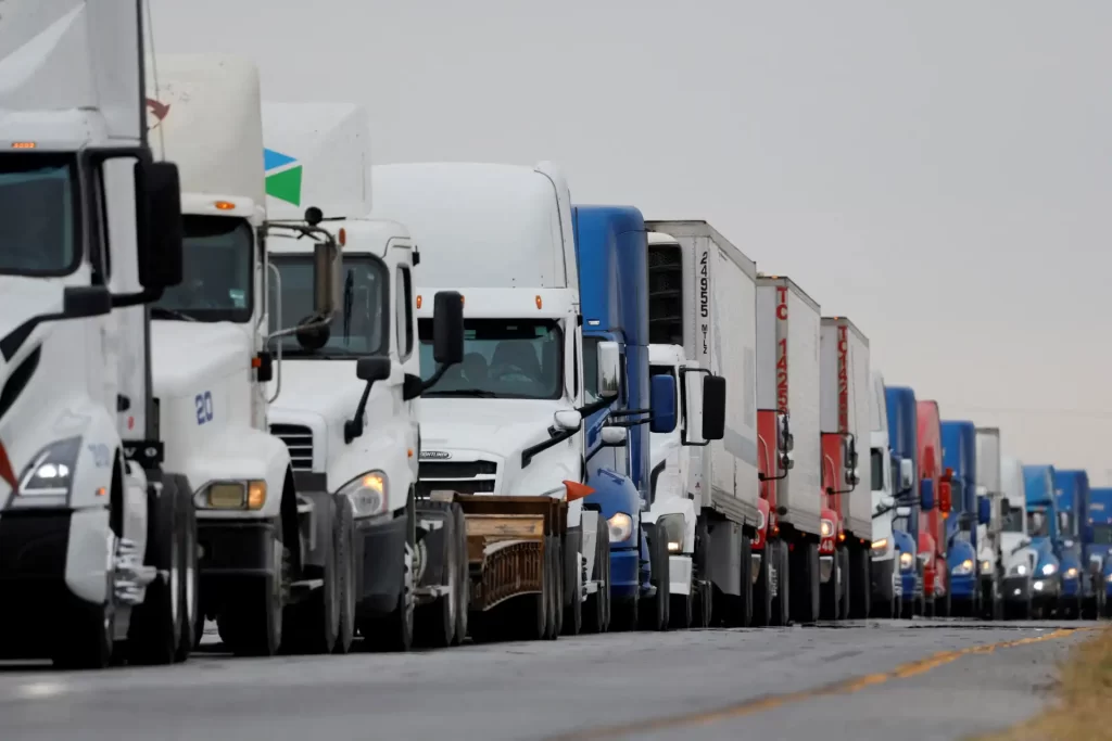 Fila de caminhões pesados em estrada, demonstrando a importância do transporte rodoviário e o movimento do setor logístico.