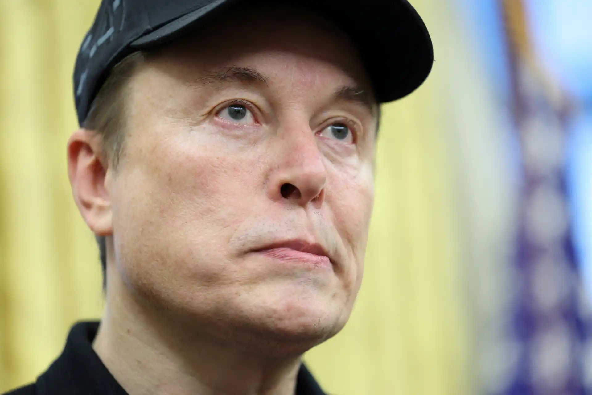 Elon Musk em evento com expressão pensativa, destacando sua influência como empreendedor e líder innovador no setor tecnológico.