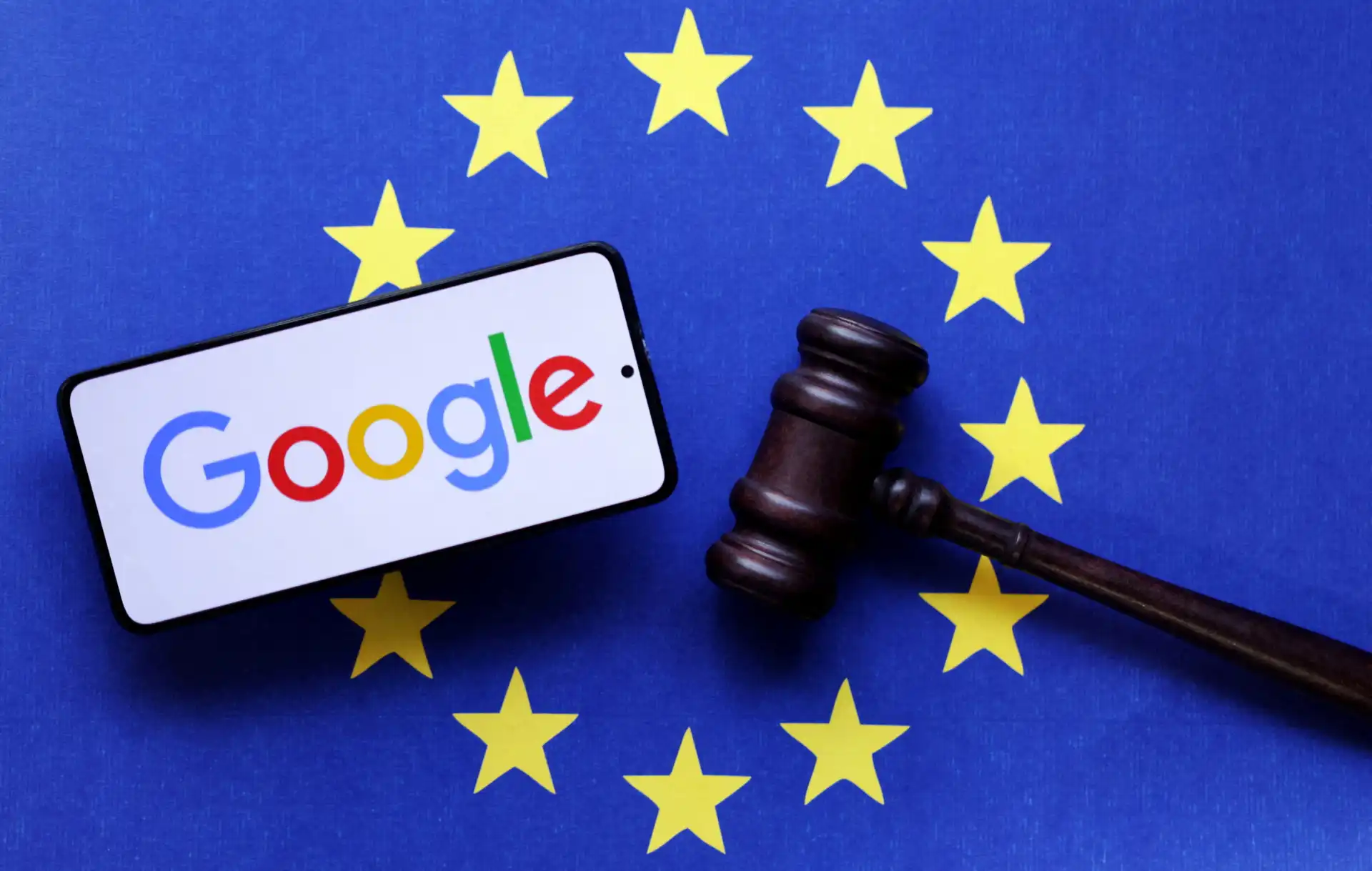 Imagem mostrando um smartphone com o logo do Google ao lado de um martelo de julgamento sobre um fundo azul com estrelas amarelas, representando a legislação na Europa.
