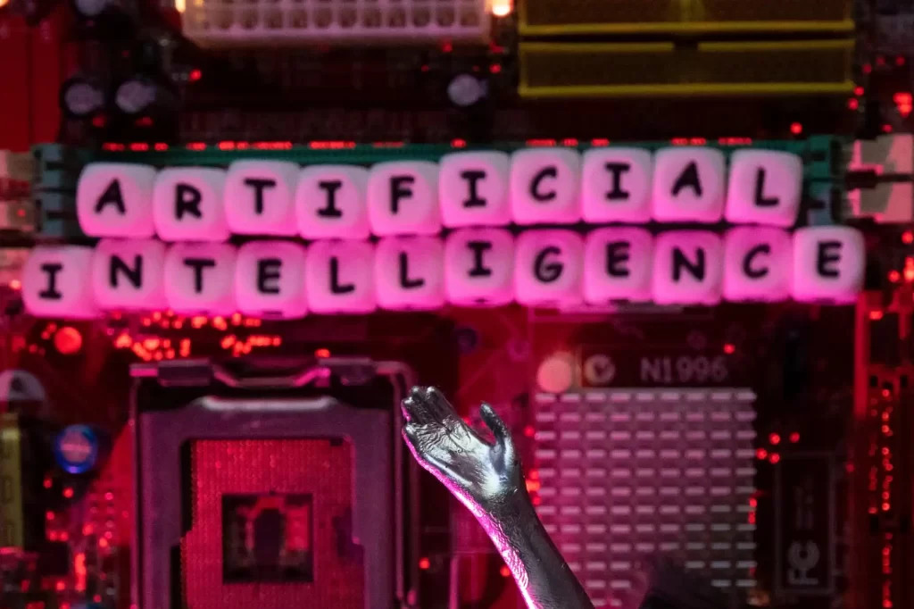 Imagem representativa da inteligência artificial com letras em uma placa-mãe. A palavra 'Artificial Intelligence' está destacada com fundo eletrônico e iluminação vibrante.