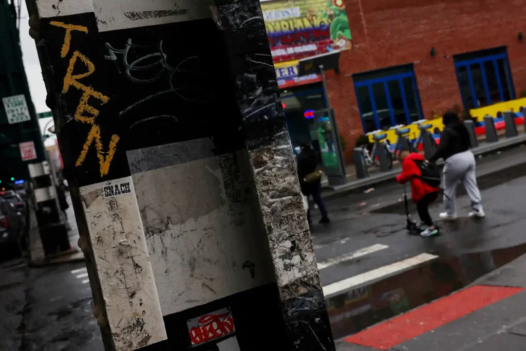 Imagem capturando uma cena urbana com o grafite 'TREN' em destaque em um poste, revelando o cotidiano e a cultura da cidade em um dia chuvoso.