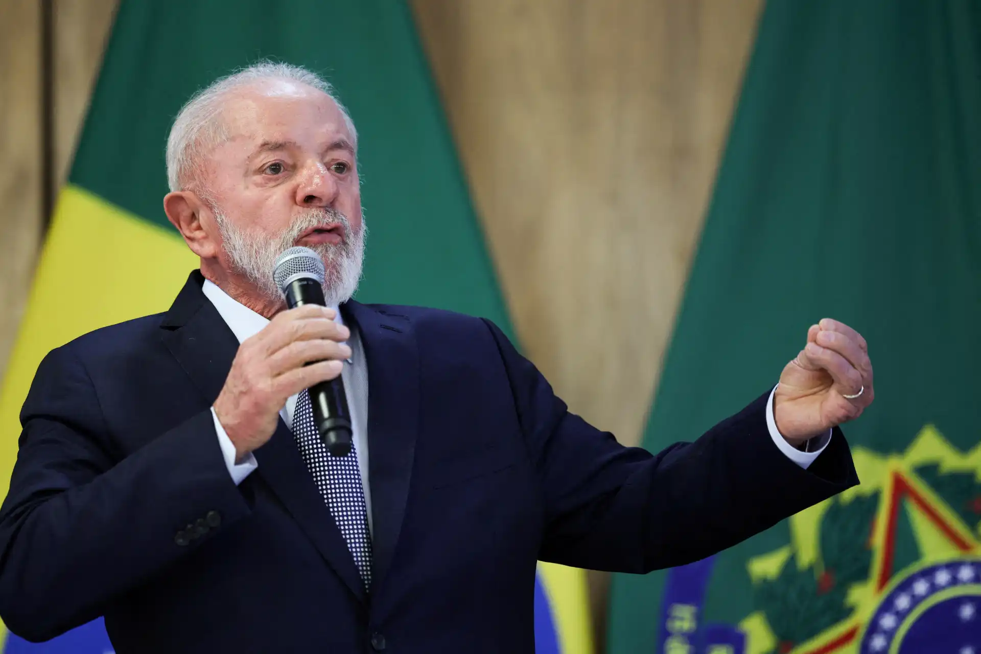 Lula da Silva em evento oficial, discursando com microfone, ao fundo bandeiras do Brasil, em momento de interação com o público. Importância do discurso para a política brasileira.