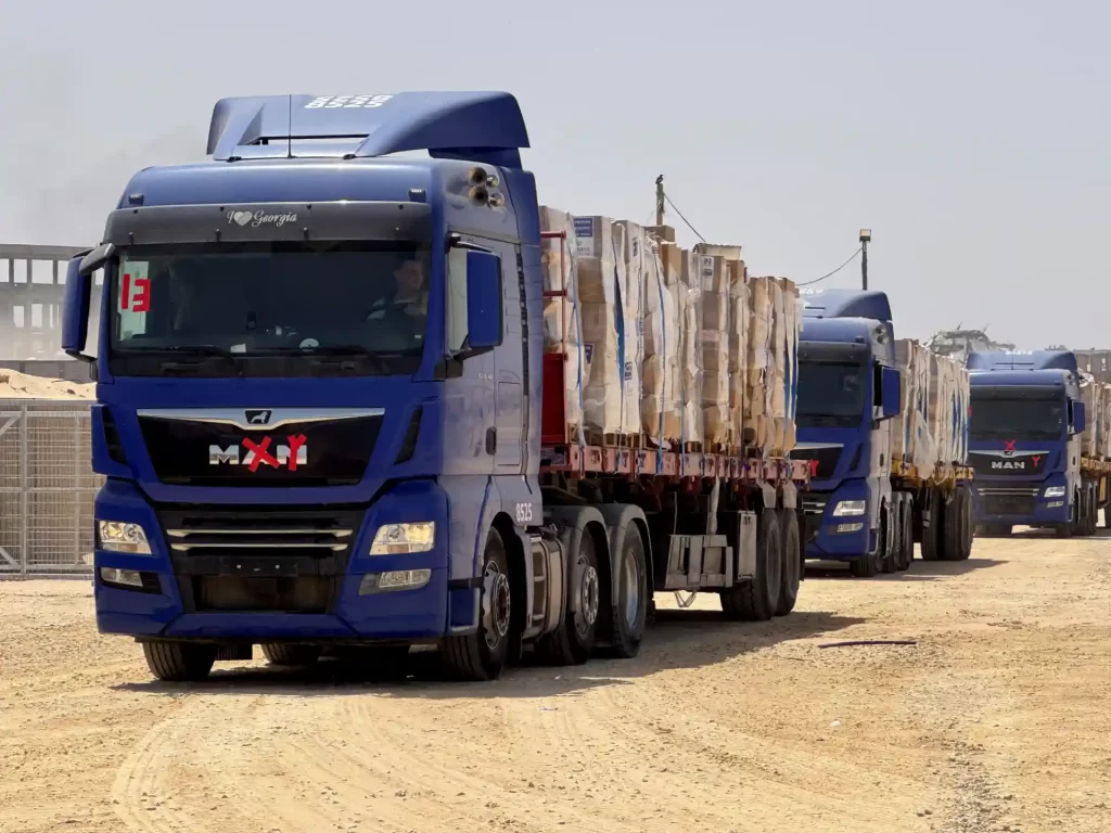 Caminhões de carga de alta capacidade de transporte de mercadorias, alinhados em uma estrada de terra em ambiente de trabalho.