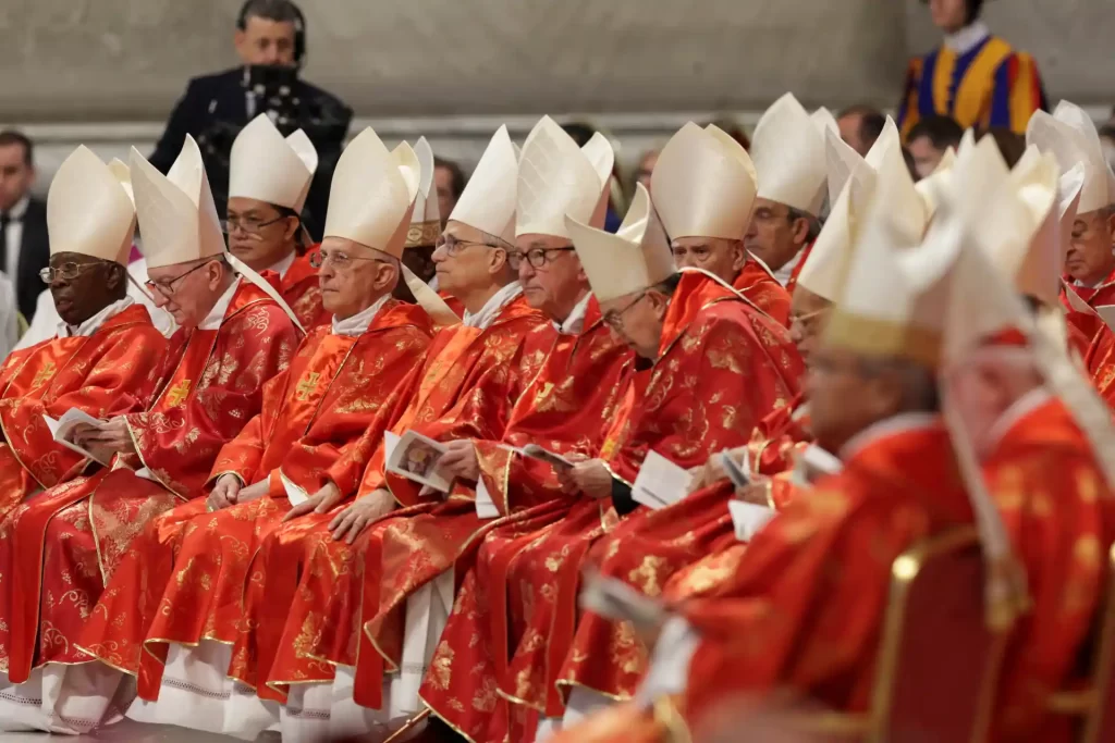 Cerimônia religiosa com cardeais em trajes vermelhos e chapéus brancos, refletindo tradições católicas no Vaticano.