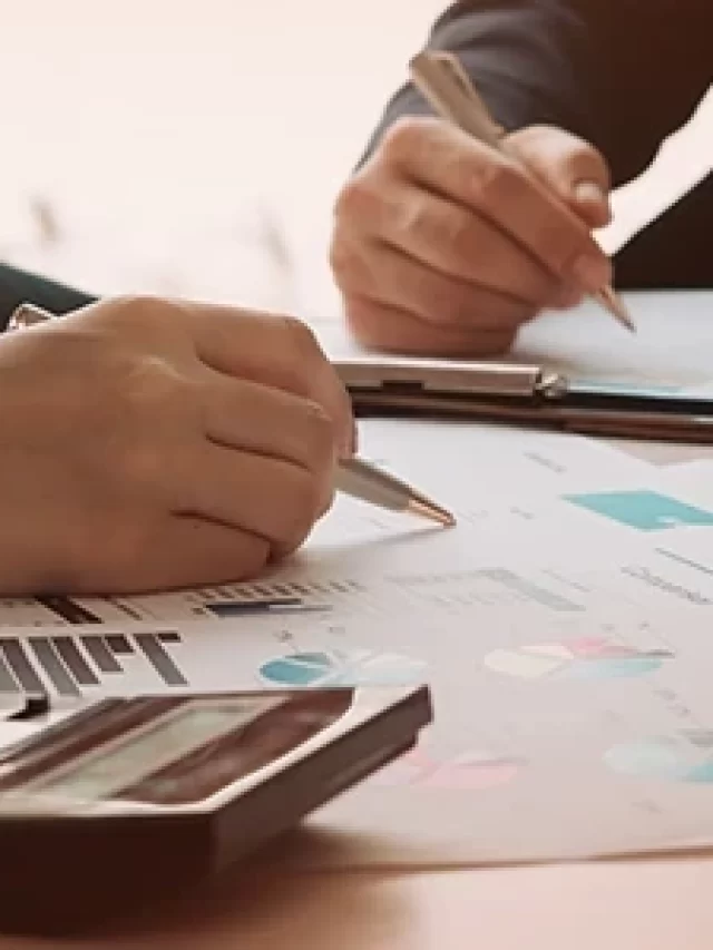 Story Imagem mostrando profissionais discutindo análises financeiras com gráficos e calculadora em ambiente de trabalho, simbolizando colaboração e planejamento financeiro.