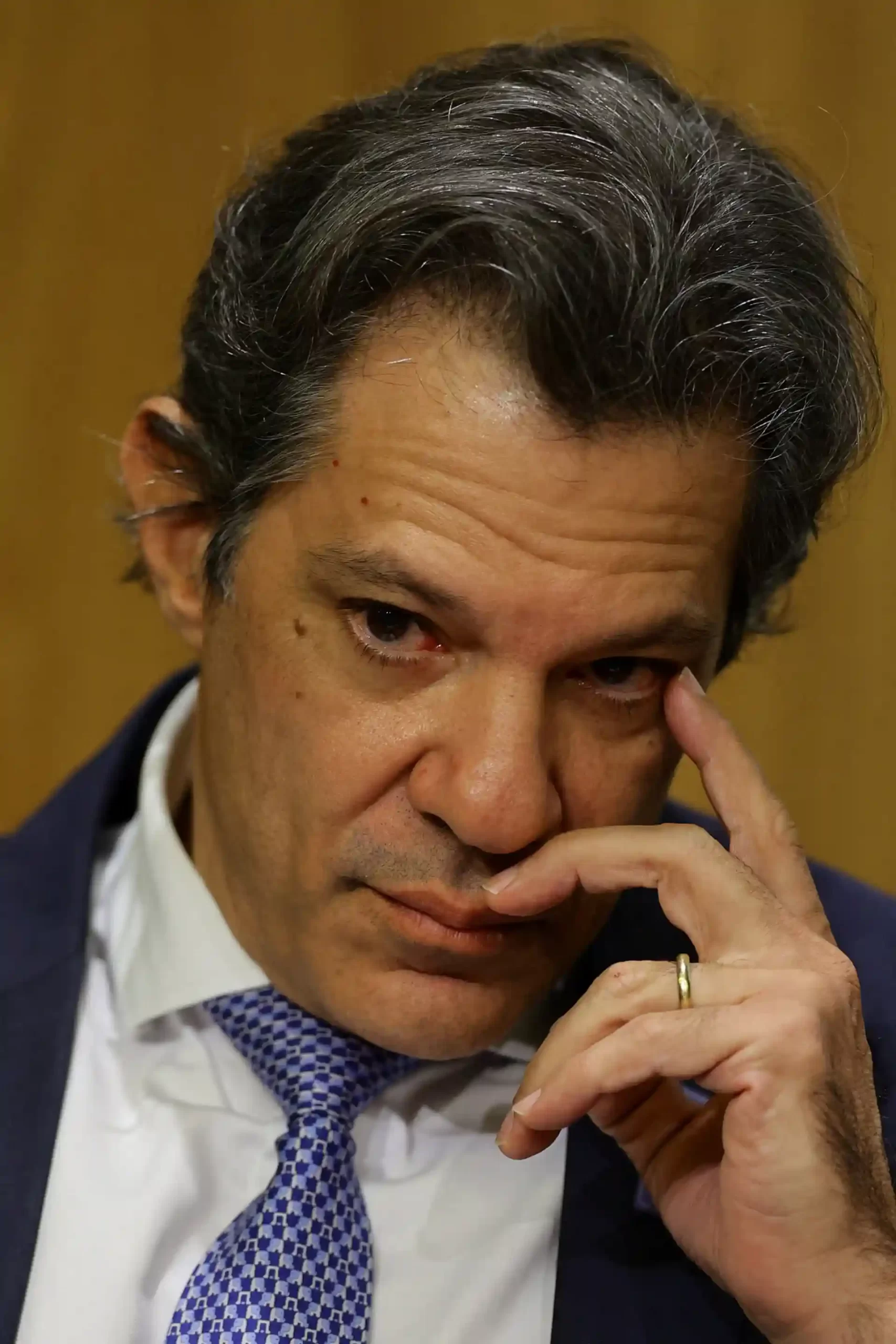 Imagem de um homem em terno, com expressão contemplativa e mão no rosto, retratando um momento de seriedade e reflexão. Importante figura pública em contexto político.