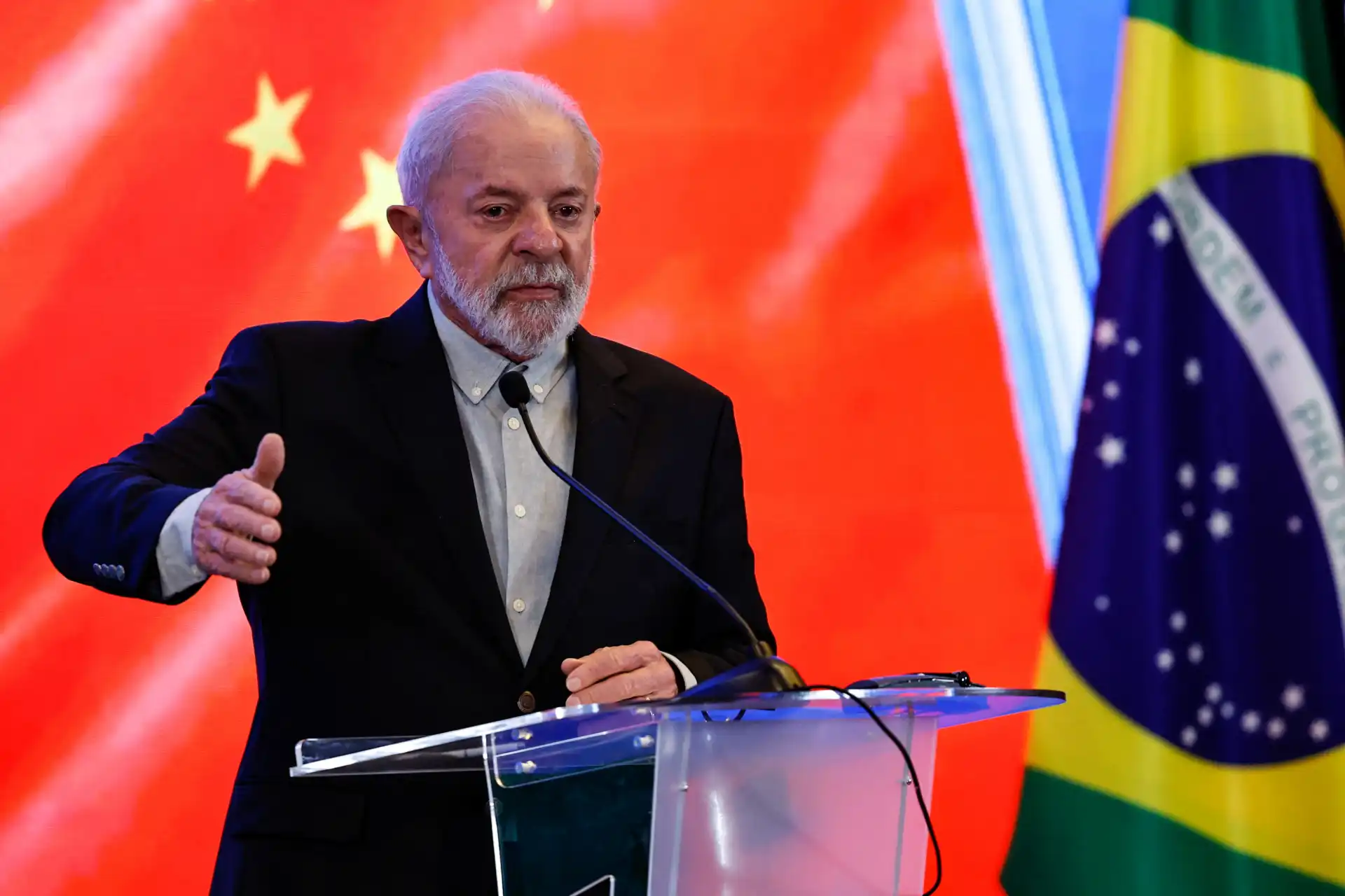 Luiz Inácio Lula da Silva durante evento com bandeira da China ao fundo, destacando a relação Brasil-China.