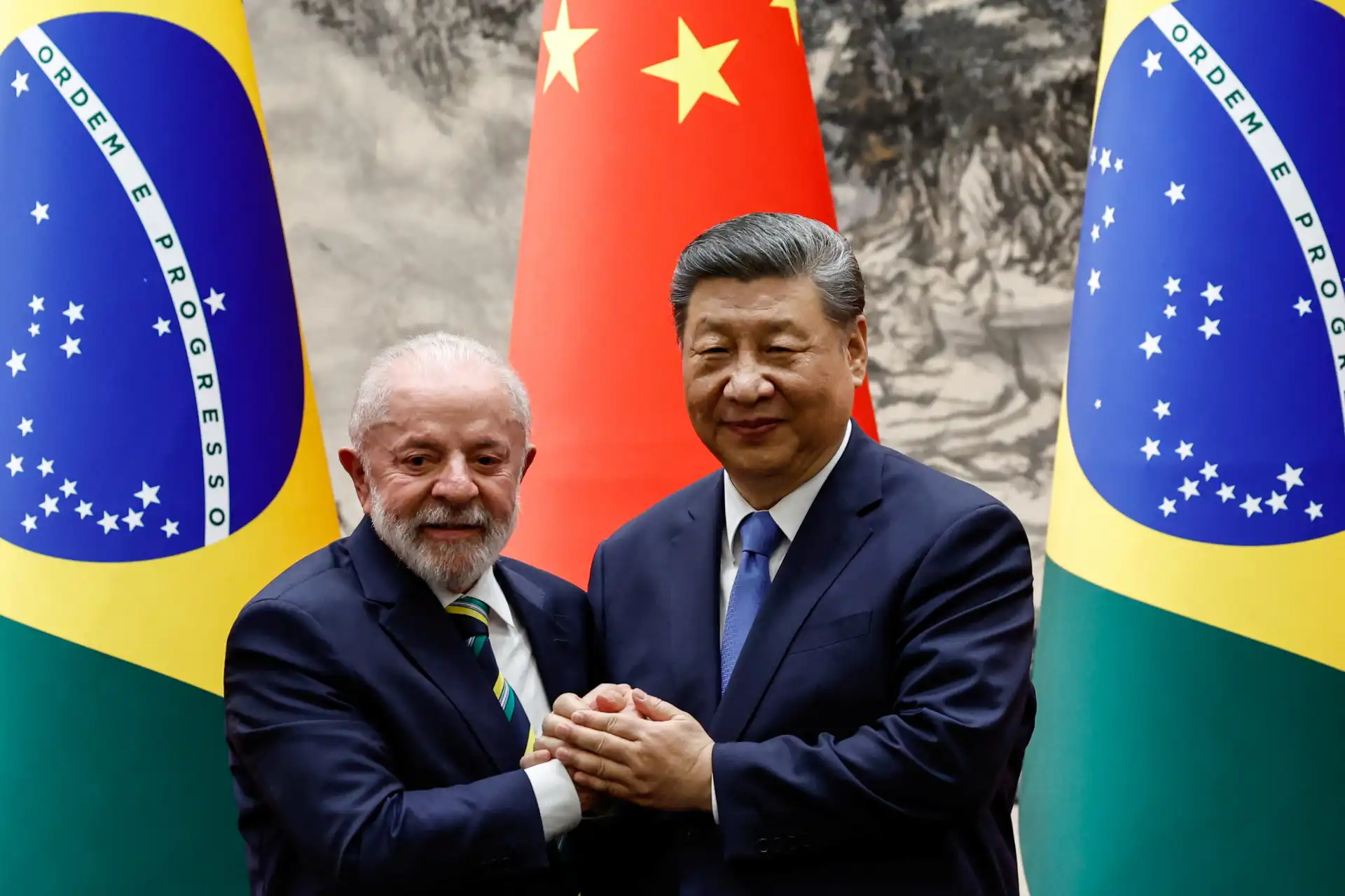 Lula e Xi Jinping em reunião, discutindo parcerias entre Brasil e China, com bandeiras do Brasil e da China ao fundo.