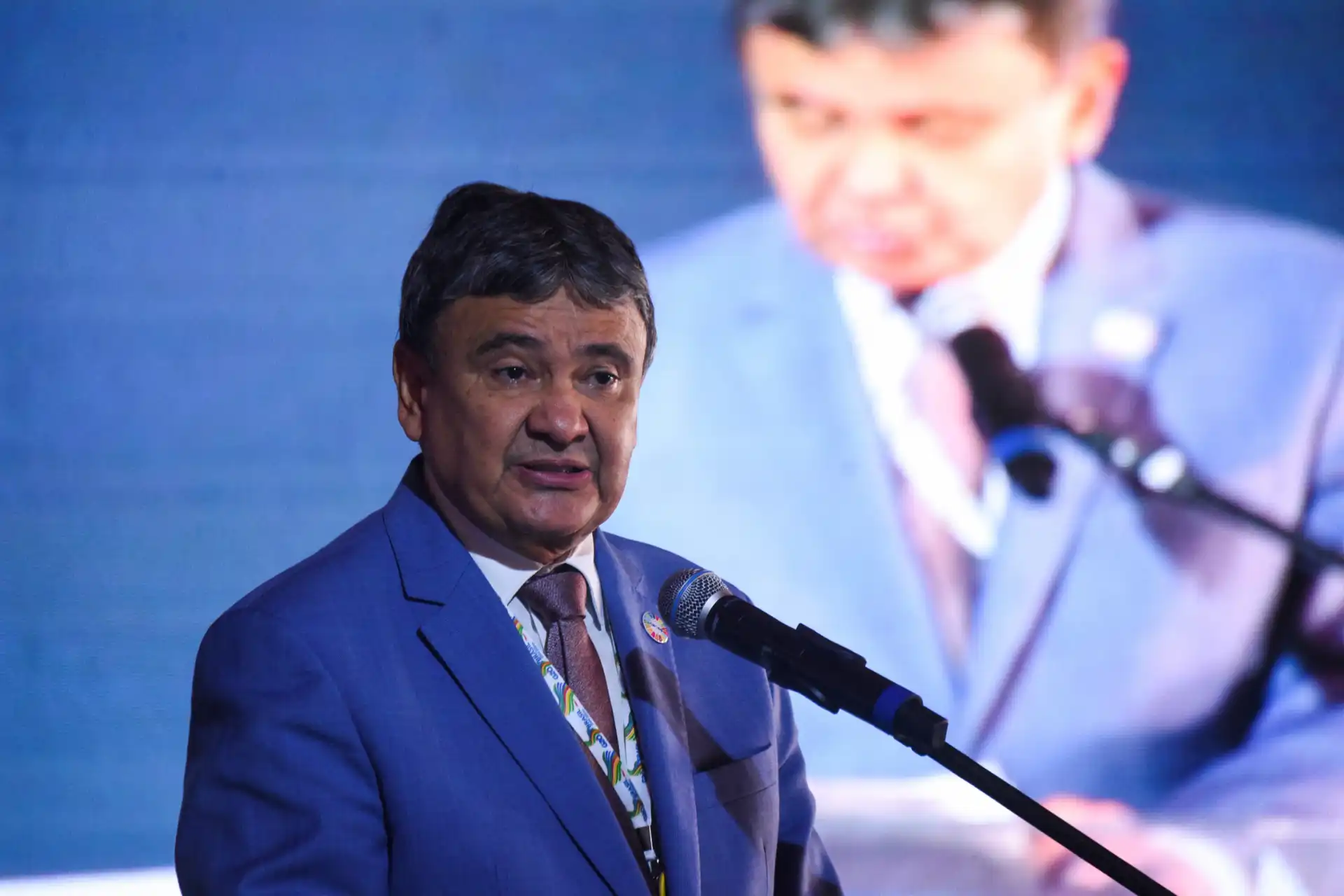 Palestrante definindo estratégias em evento, com foco em desenvolvimento e inovação, destacando conhecimentos e informando o público sobre o tema.