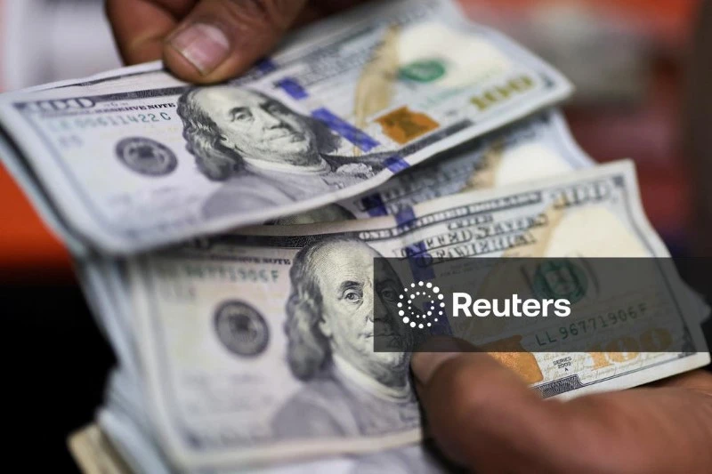 Pessoa trocando notas de dólar americano, destaque para as cédulas de 100 dólares, simbolizando temas de economia, finanças ou câmbio.