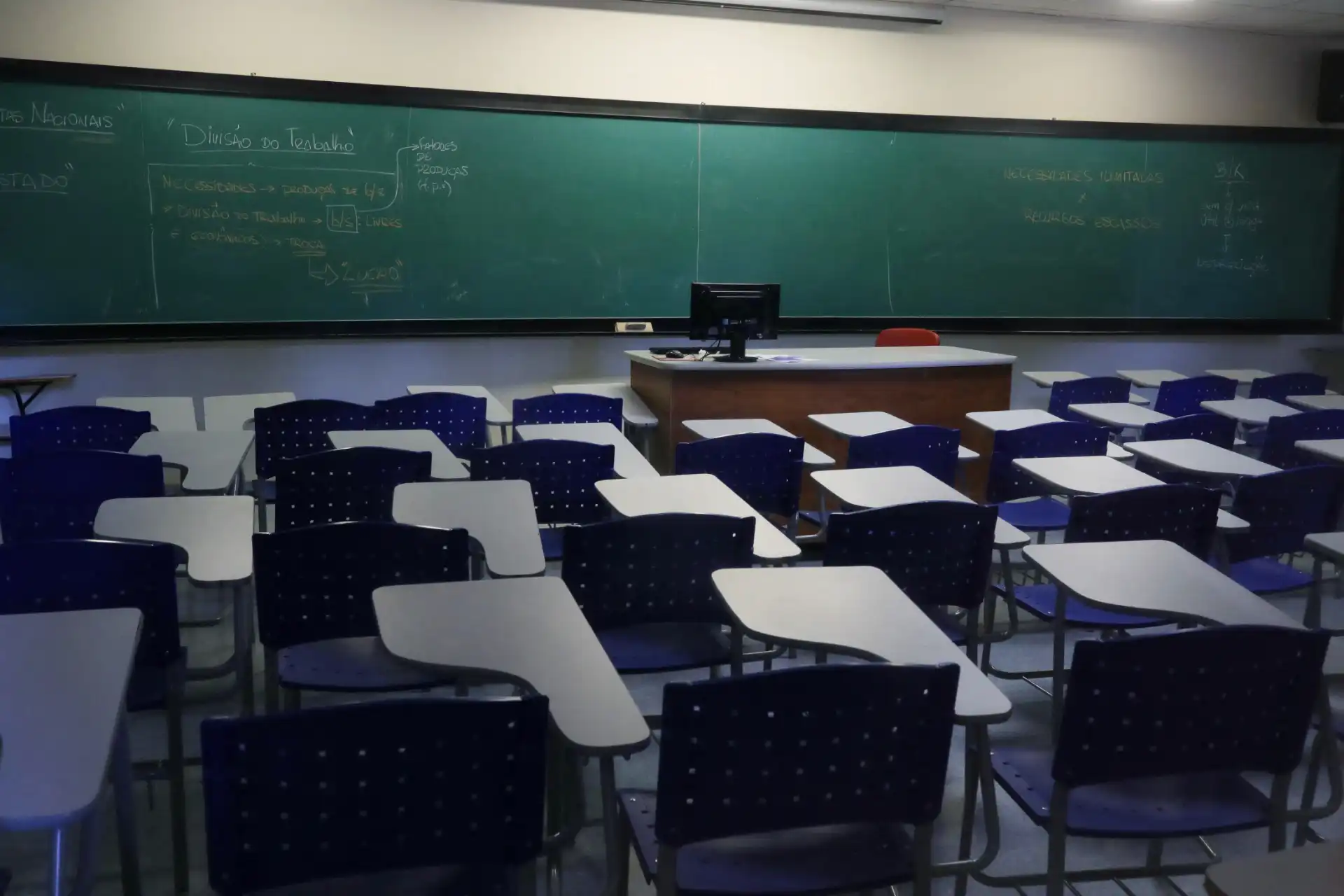 Sala de aula vazia com carteiras e quadro-negro, ambiente escolar preparado para aulas presenciais de ensino.