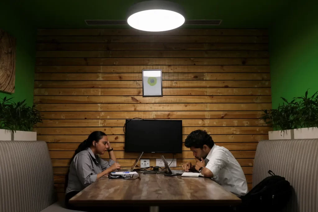 Pessoas trabalhando em um ambiente colaborativo, em uma sala com decoração moderna e aconchegante, ideal para reuniões e produtividade.