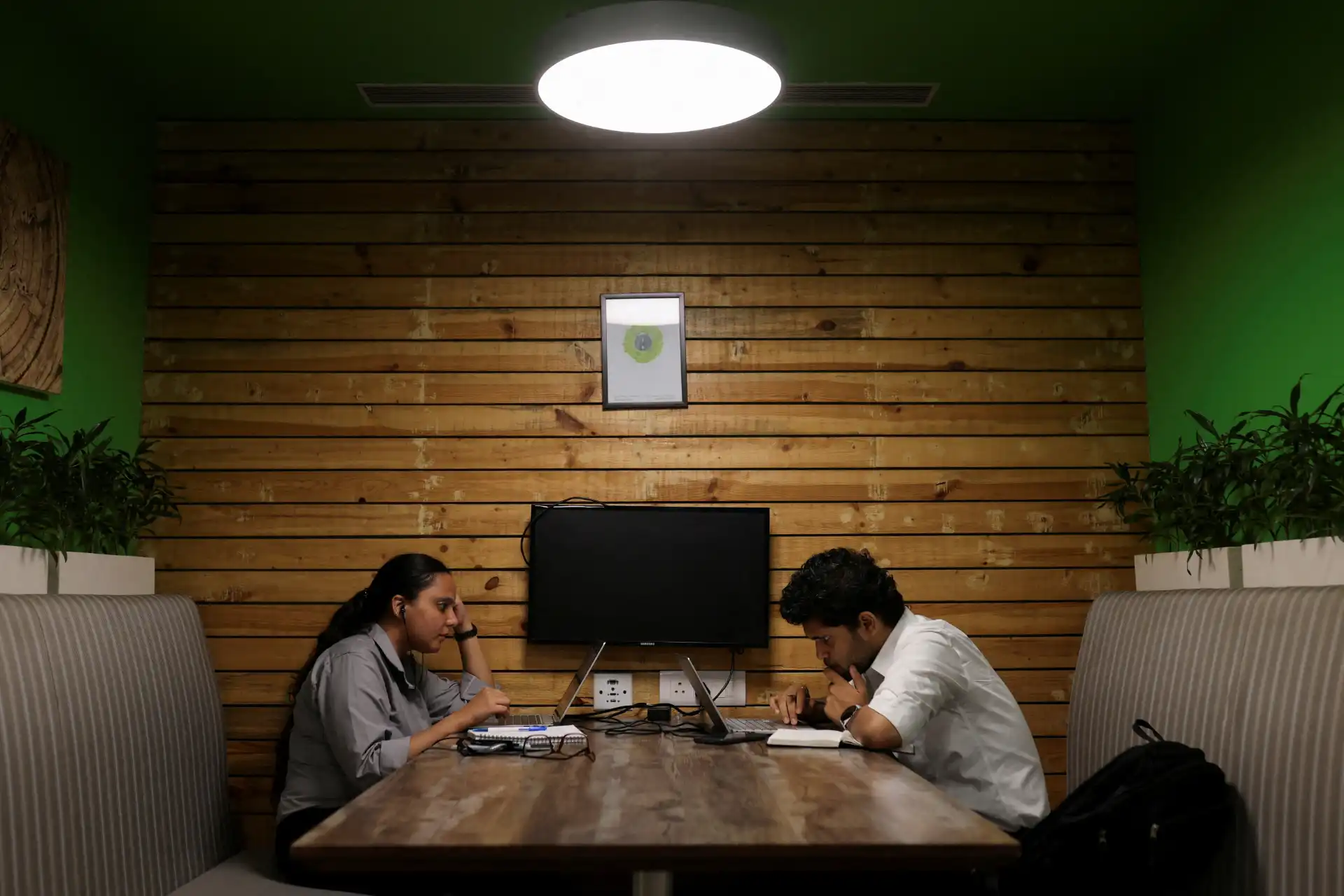 Pessoas trabalhando em um ambiente colaborativo, em uma sala com decoração moderna e aconchegante, ideal para reuniões e produtividade.