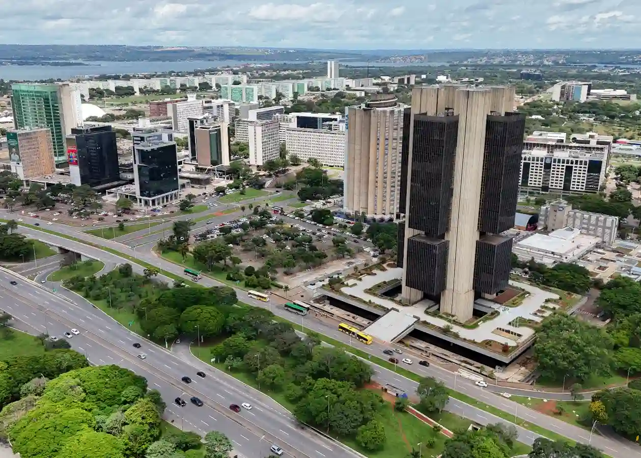 Vista aérea de um distrito financeiro moderno na cidade, com edifícios altos, ruas movimentadas e uma área verde bem cuidada. Uma cena urbana vibrante e bem planejada no Brasil.