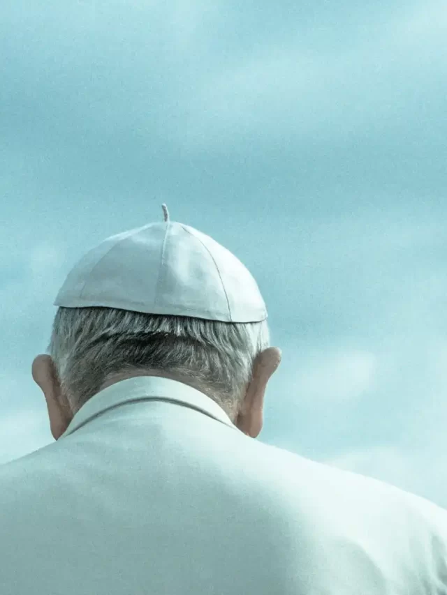 Story Imagem de um homem idoso de costas usando um chapéu branco, olhando para o céu com nuvens, simbolizando reflexão e espiritualidade.