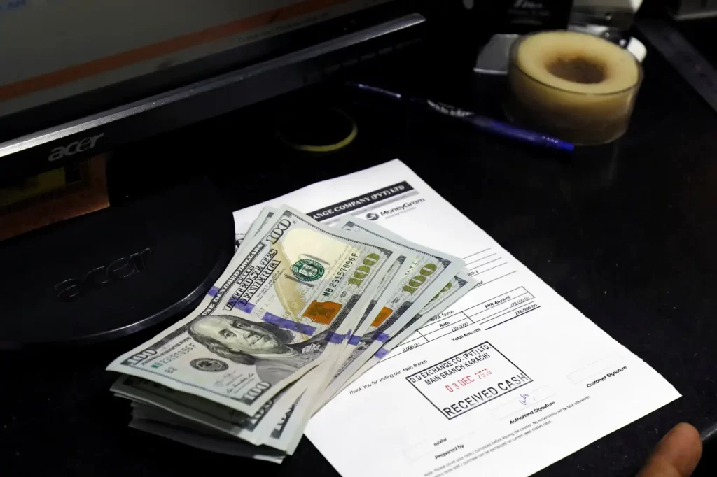 Dólar tem leve baixa na abertura com decisões de BCs e tensões no Oriente Médio em foco Foto de dinheiro em espécie e recibo de pagamento nesteira de escritório com objetos de escritório ao fundo.