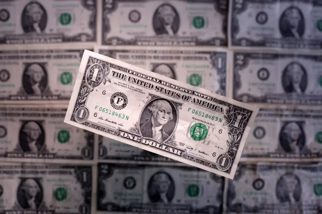 Dólar americano destaca-se no centro de várias notas de dinheiro ao fundo, simbolizando economia, moeda forte e valor financeiro. Imagem ideal para artigos sobre investimento e câmbio.