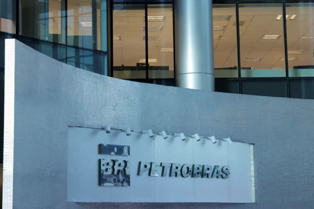 Fachada da Petrobras com logo na parede de um edifício moderno de vidro e concreto, refletindo o ambiente ao redor em São Paulo