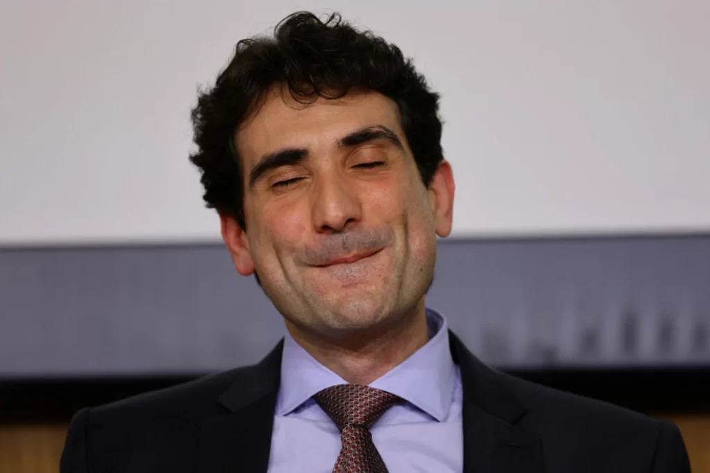 Homem de terno e gravata sorrindo com expressão de satisfação, em ambiente interno. Ideal para ilustrar temas de negócios, liderança ou profissionais bem-sucedidos.