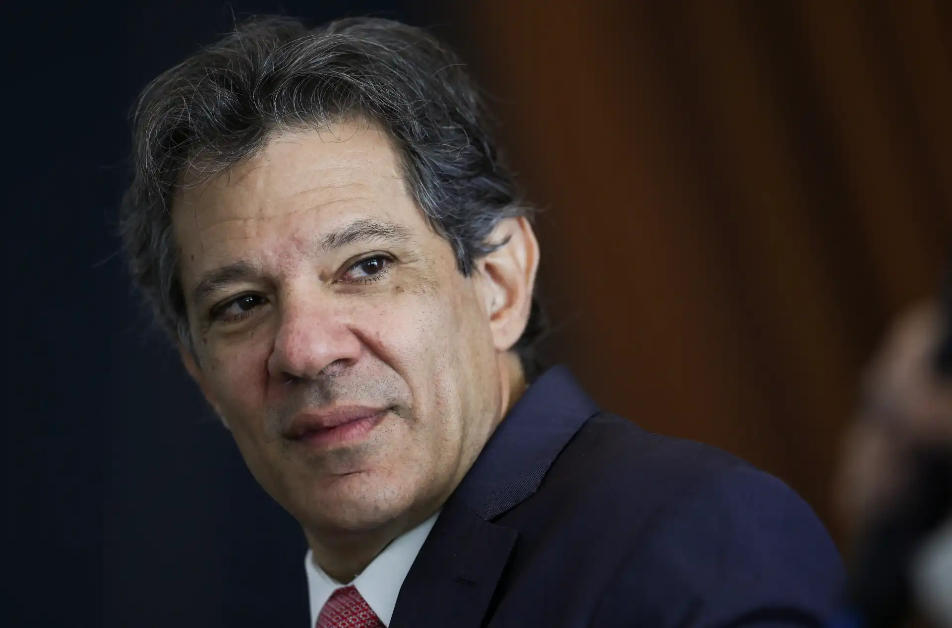 Imagem de um homem de cabelo escuro e expressão séria, vestindo terno, representando uma figura de autoridade ou liderança