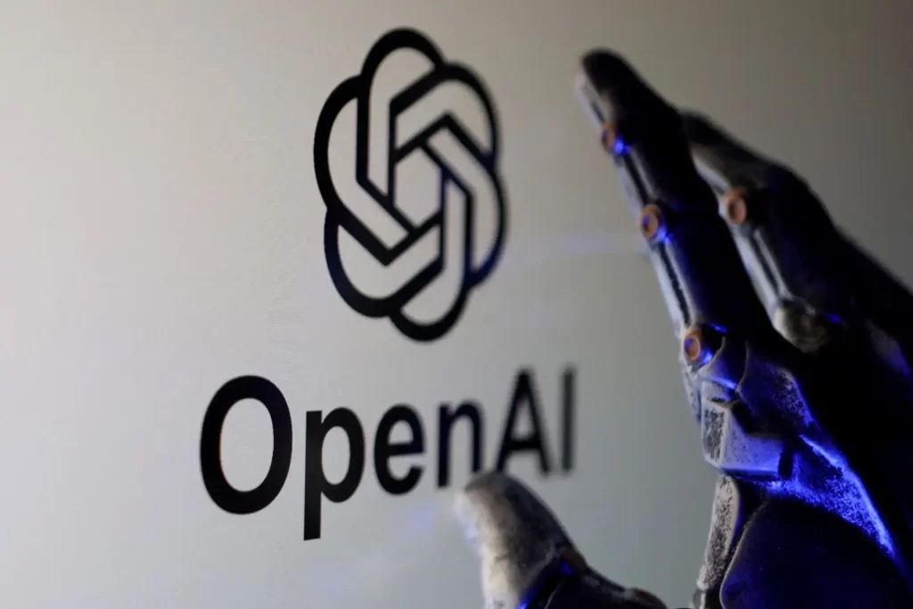 Imagem de uma mão robótica segurando um dispositivo próximo ao logotipo da OpenAI, destacando a tecnologia de inteligência artificial avançada. A imagem transmite inovação e o uso de IA no desenvolvimento de soluções inteligentes.