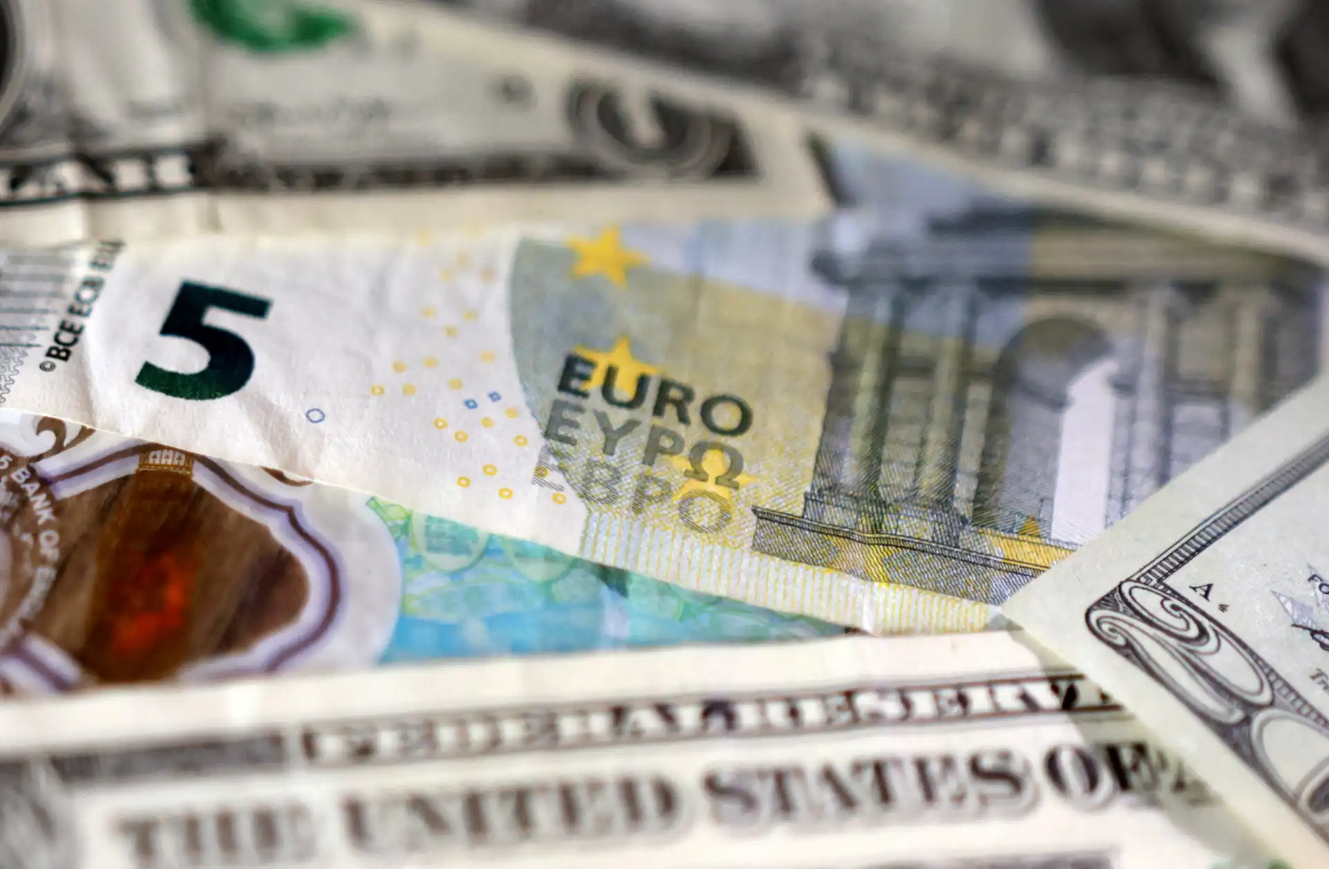 Imagem de notas de dinheiro, incluindo euro e dólar, destacando valor monetário e câmbio internacional.