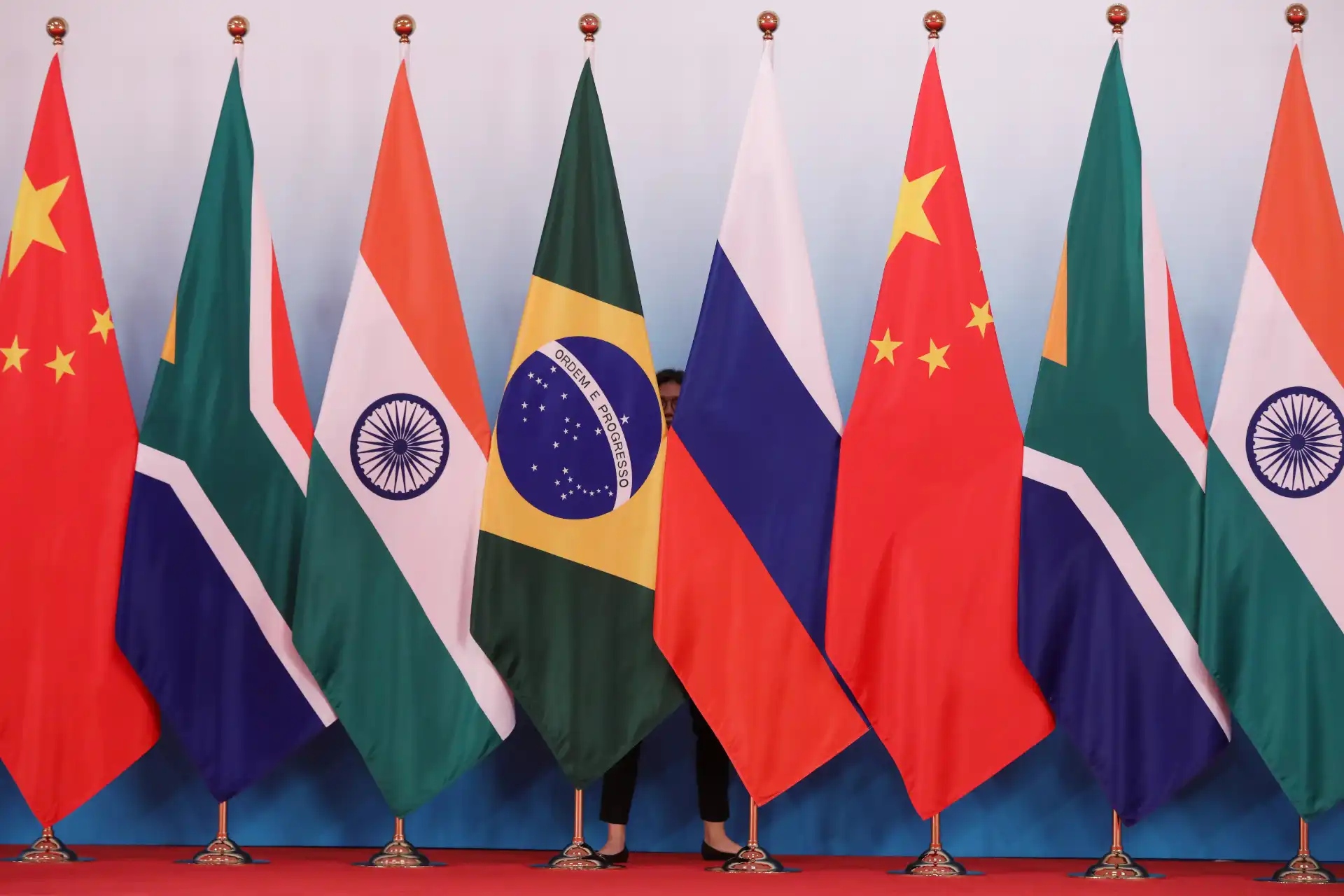 Foto mostrando várias bandeiras de países, incluindo Brasil, Índia, China, Rússia, África do Sul, e outros, em um evento internacional, simbolizando cooperação e união entre nações.