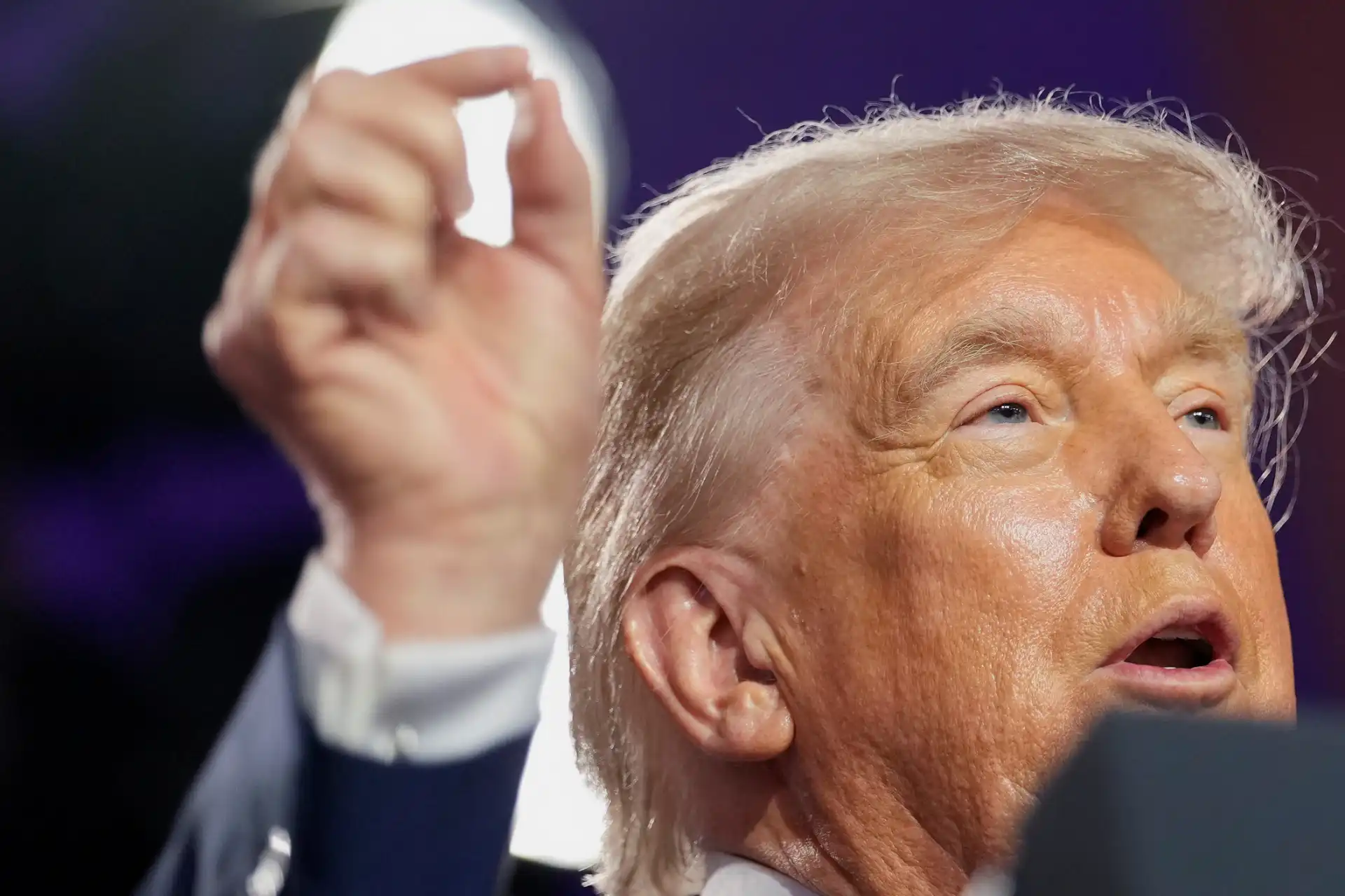 Imagem do ex-presidente Donald Trump durante discurso político, destacando sua expressão facial e gesto com a mão, em evento público.