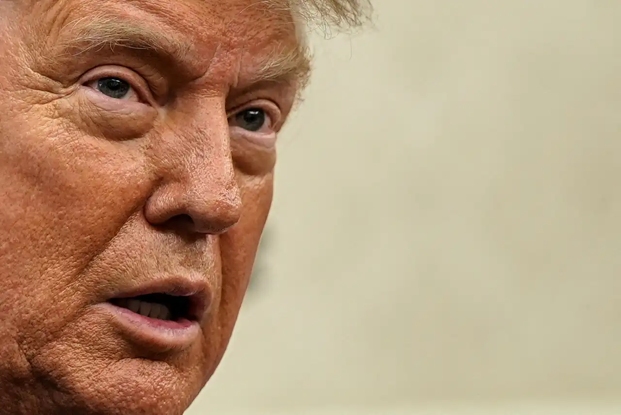 Imagem de Donald Trump, ex-presidente dos Estados Unidos, com expressão facial séria e cabelo loiro característico, retrato próximo.