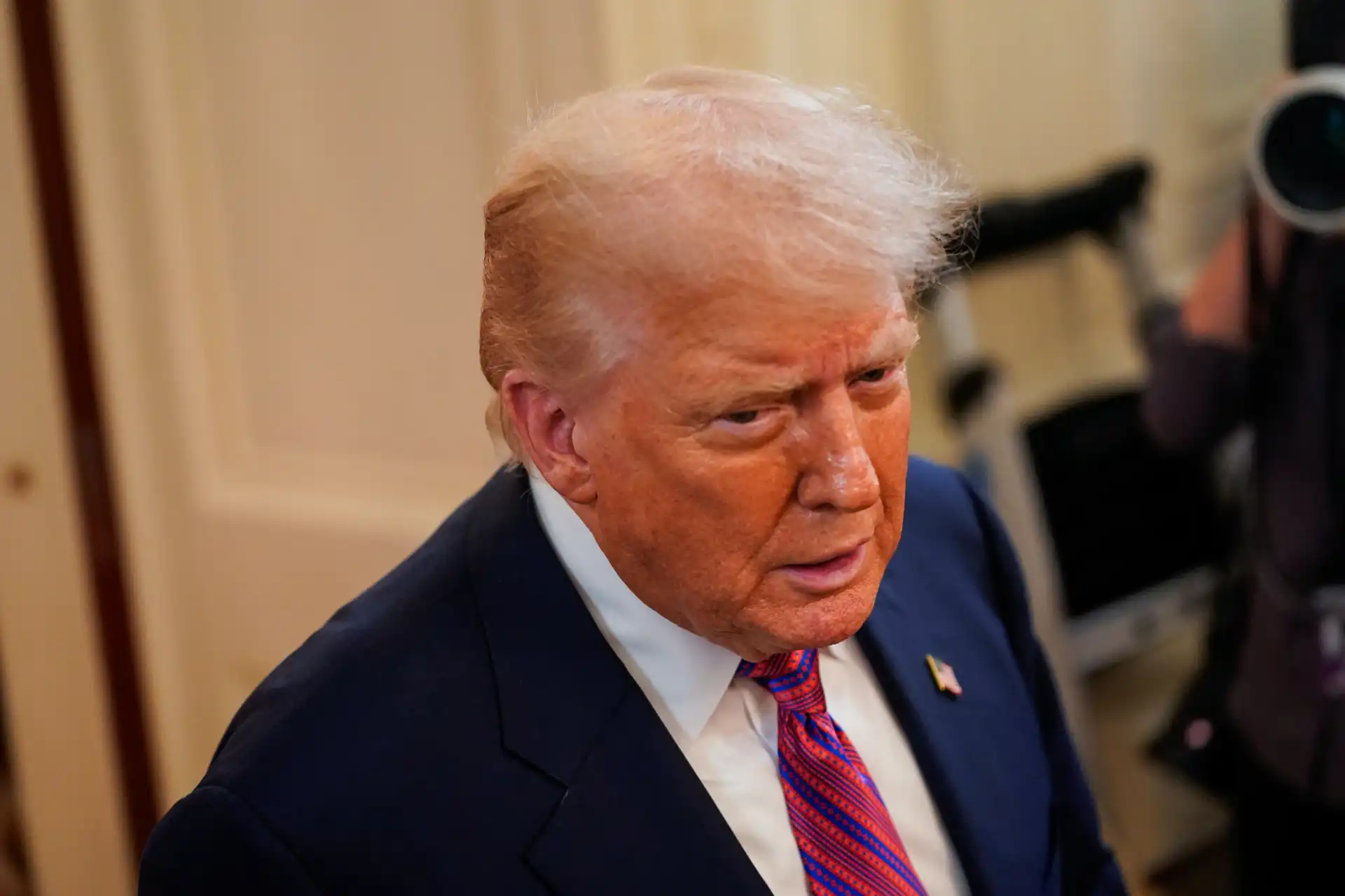 Imagem de Donald Trump com expressão séria, vestindo terno e gravata, em evento oficial ou entrevista, destacando sua postura e aparência distinta.