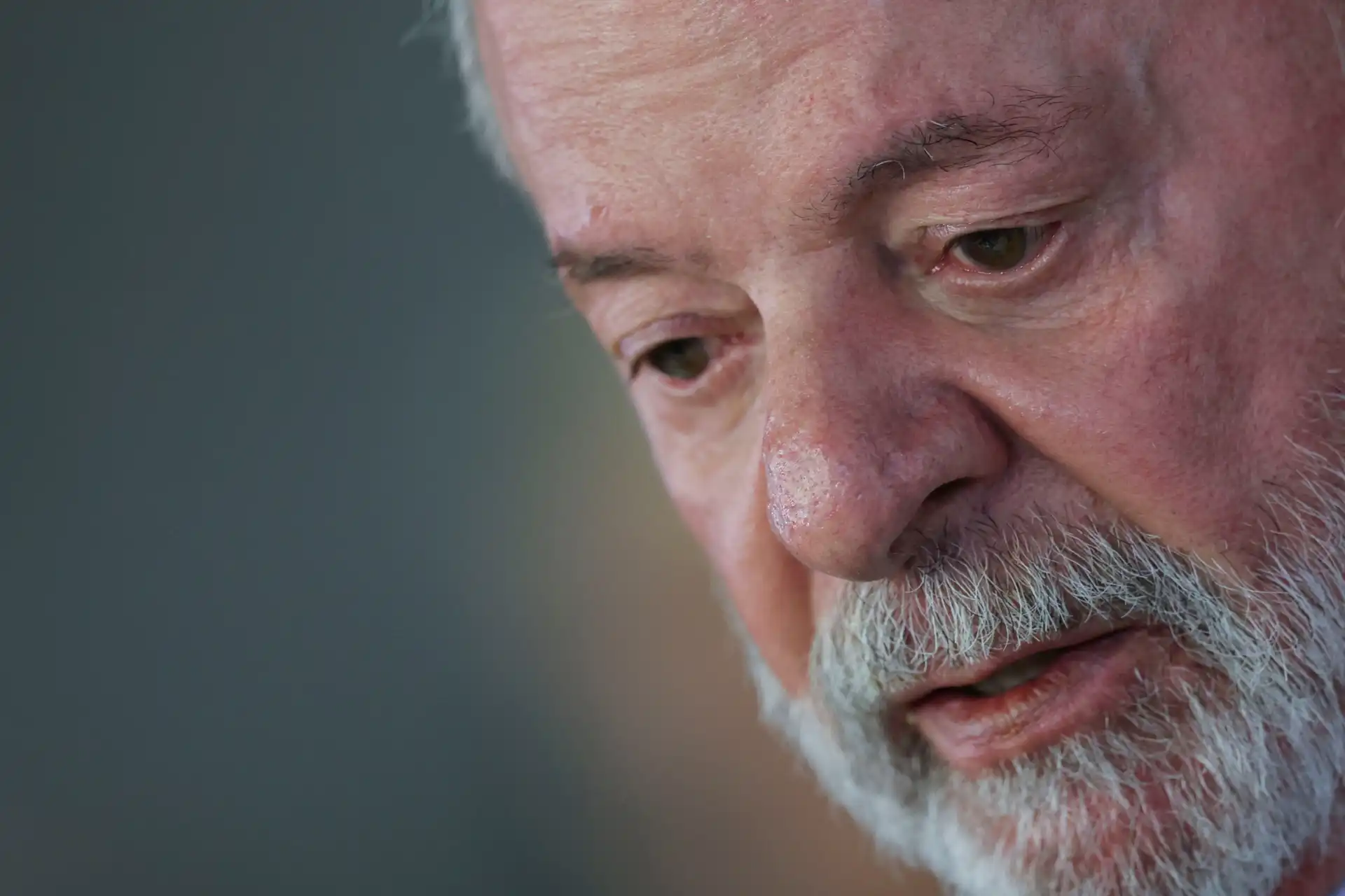Imagem de um homem idoso com barba grisalha, expressão pensativa, destacando detalhes do rosto, como linhas de expressão e cabelo branco.