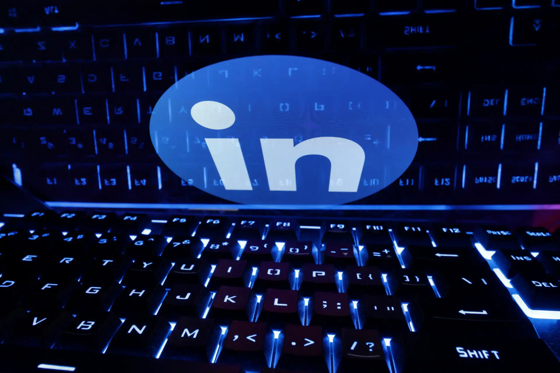 Imagem com LED de teclado de computador iluminado em azul e logo do LinkedIn destacado ao centro, simbolizando conexões profissionais e rede social.