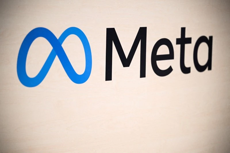 Logo da Meta na parede, destacando o símbolo do infinito azul e o nome Meta ao lado.