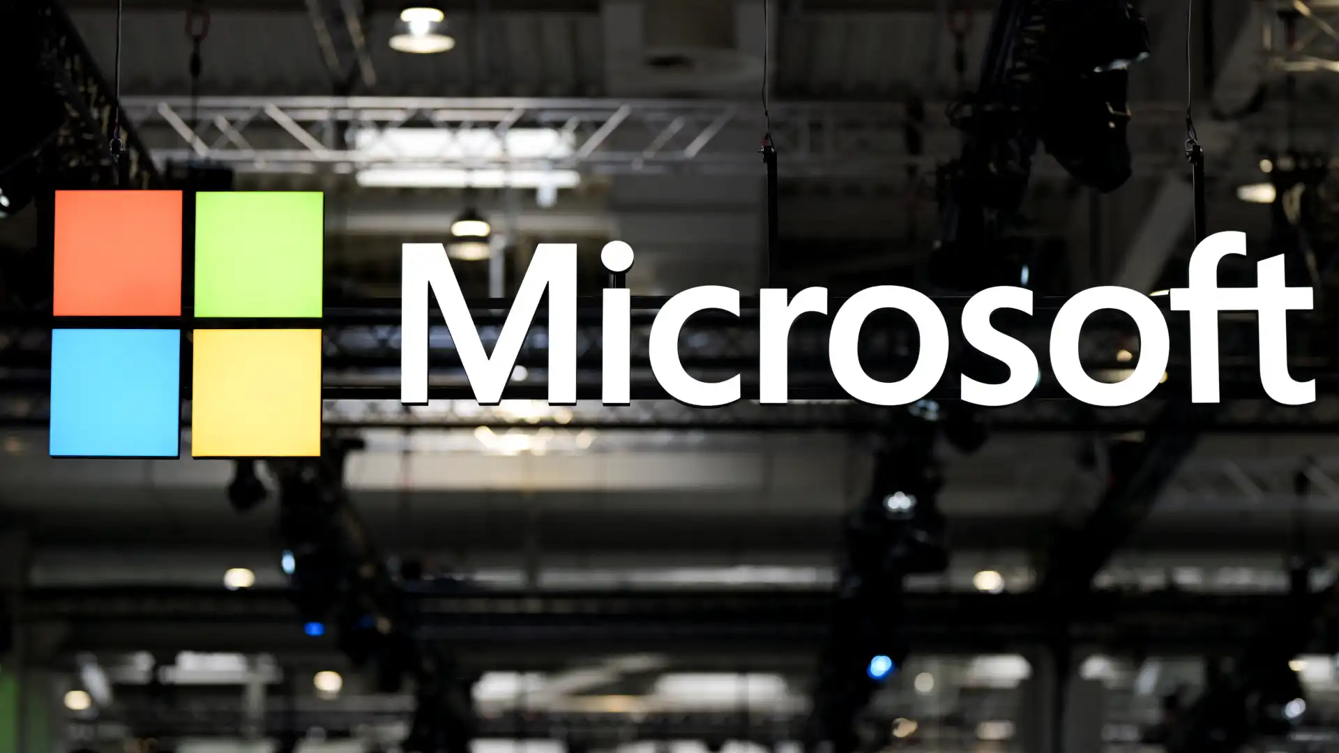 Logotipo da Microsoft exposto em uma parede no ambiente de uma conferência ou evento de tecnologia, destacando a marca do gigante de tecnologia