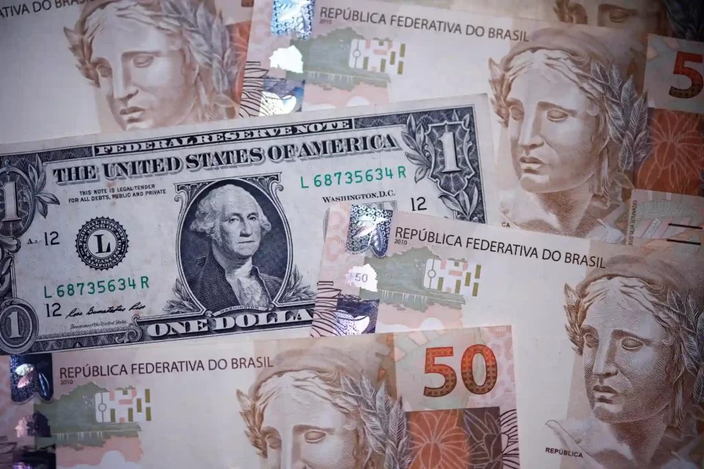 Notas de dinheiro brasileiro e dólar americano em destaque, com foco na diversidade de moedas e sua importância econômica.