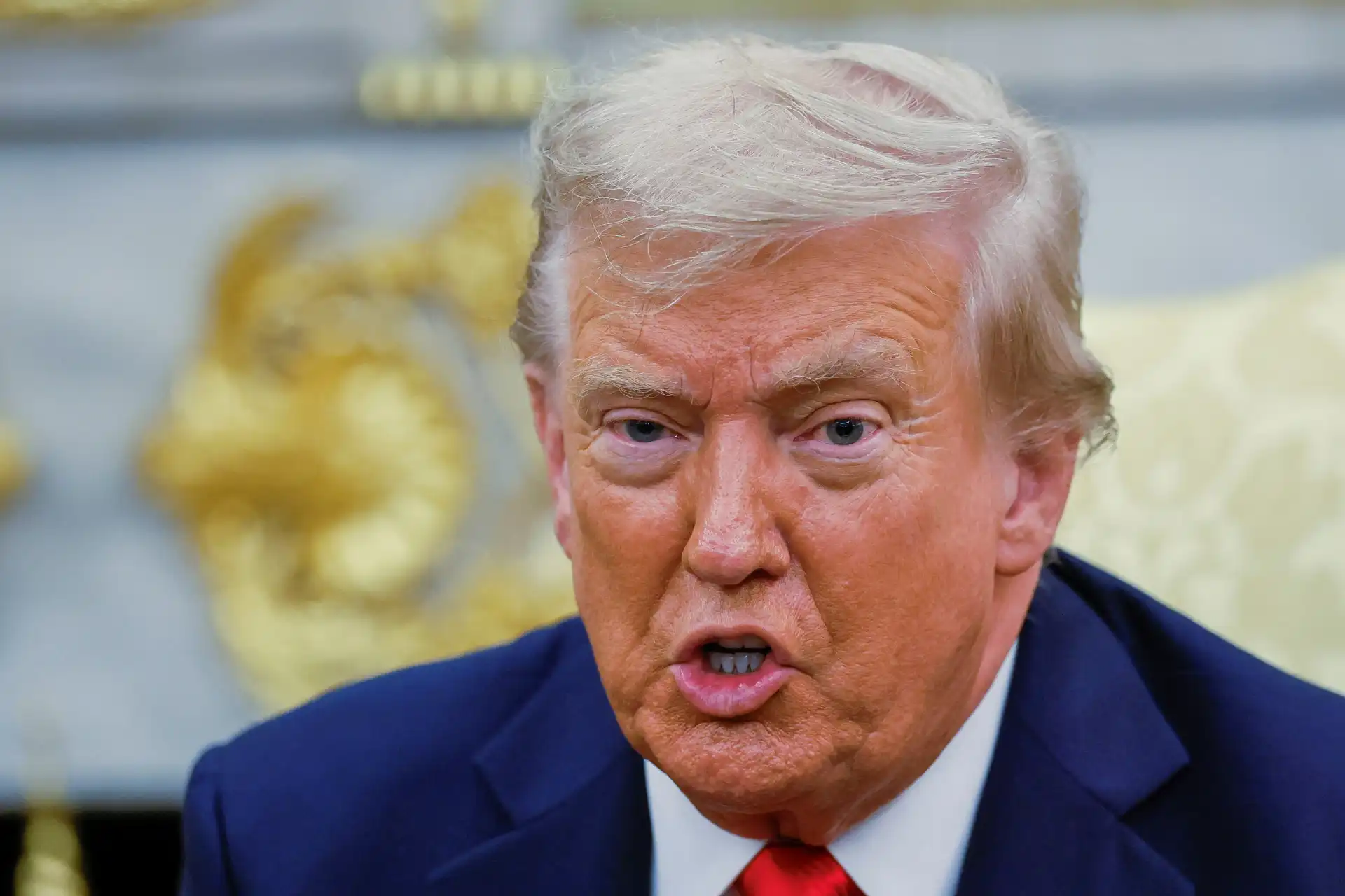 Imagem de Donald Trump, ex-presidente dos Estados Unidos, fazendo uma expressão facial durante uma entrevista ou discurso, com fundo que parece um ambiente formal.